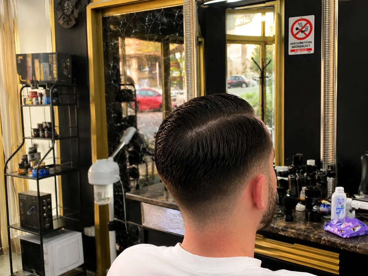 Clean fade, back view in the mirror